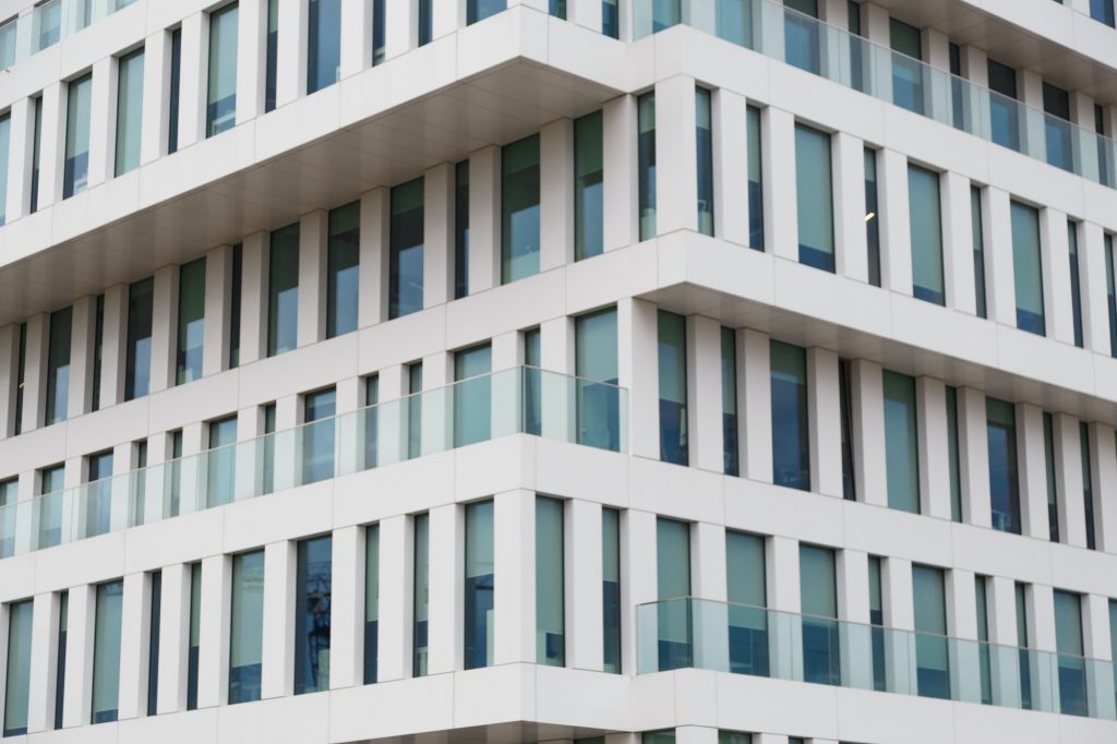 Texture of the modern facade. Perspective view of a white concrete facade with blue windows